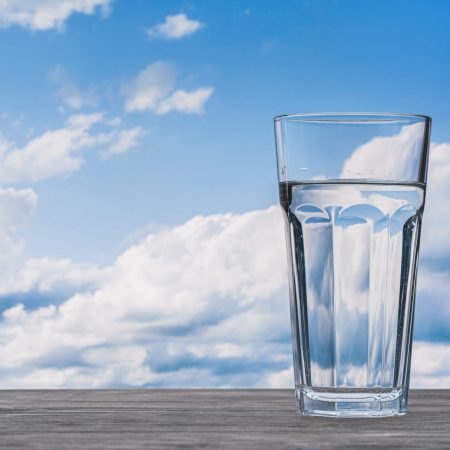 Glass,With,Water,On,Wooden,Table.,Blue,Sky,With,White